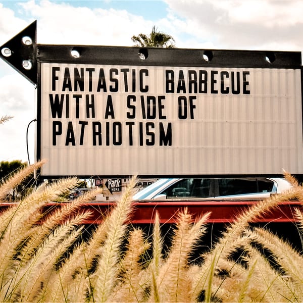 A drive-in sign for American Way Smokehouse reads "FANTASTIC BARBECUE WITH A SIDE OF PATRIOTISM".